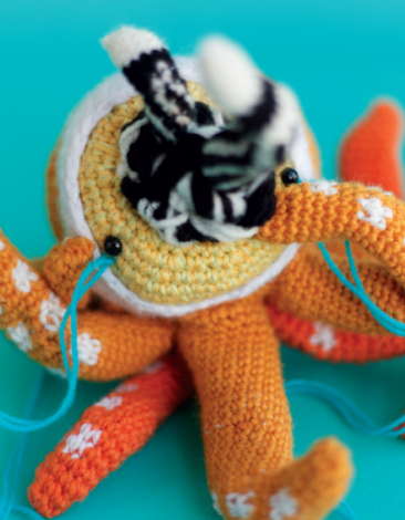 Crocheted doll called Amigurumi. The doll has the shape of an octopus with many heads and snakes coming out from its mouth.