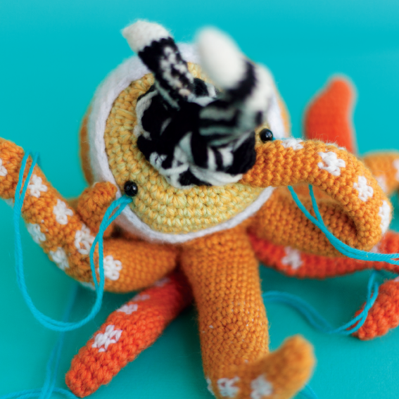 Crocheted doll called Amigurumi. The doll has the shape of an octopus with many heads and snakes coming out from its mouth.