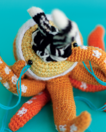 Crocheted doll called Amigurumi. The doll has the shape of an octopus with many heads and snakes coming out from its mouth.